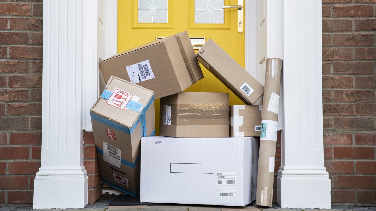 Várias caixas de encomendas empilhadas em frente a uma porta amarela