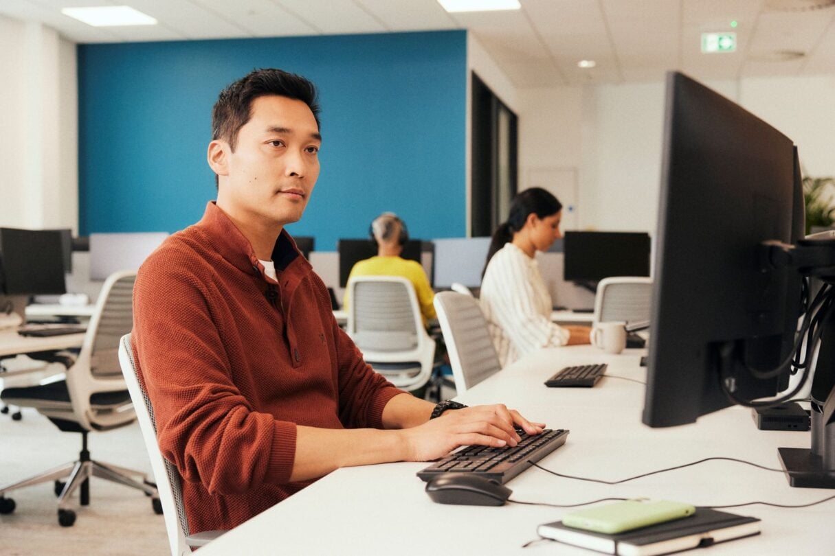 Rapaz a trabalhar no escritório, concentrado no computador.