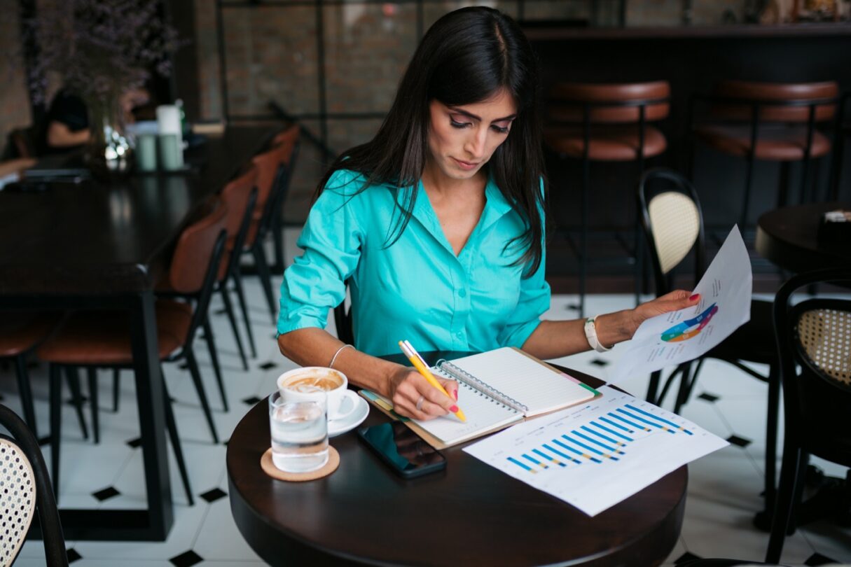 Uma jovem mulher a trabalhar, revisando documentos em sua mesa.